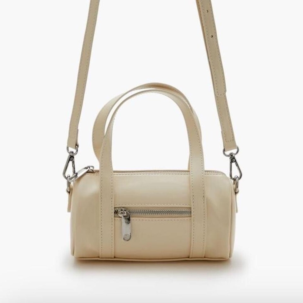 Cream mini cylinder bag‎ with silver hardware, featuring a zip closure